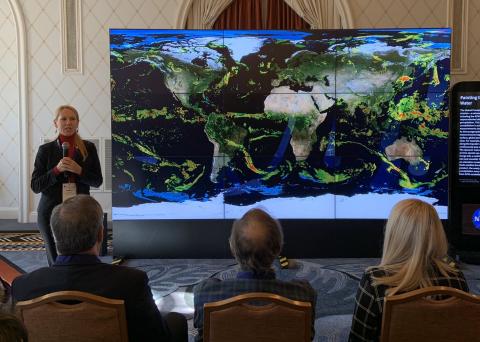 Person from NASA presenting in front of a map of the world